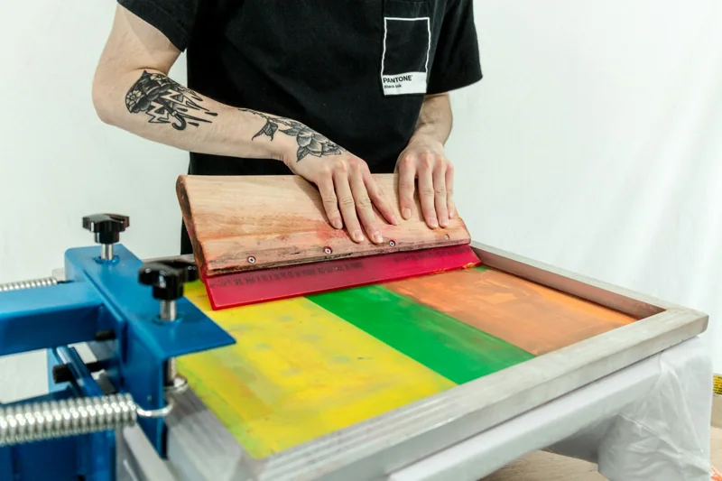 A screen printer applying ink to a garment with a squeegee